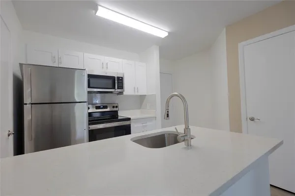 a kitchen with stainless steel appliances granite countertop a refrigerator a sink a stove top oven and a refrigerator