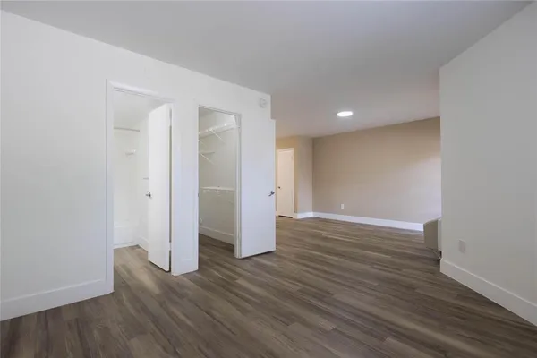 a view of an empty room with wooden floor and closet