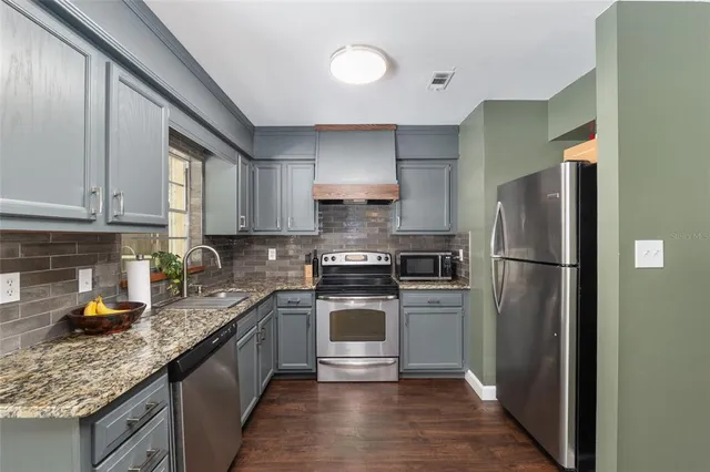 a kitchen with granite countertop stainless steel appliances a stove and a microwave