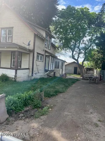 a view of a house with a yard and large tree
