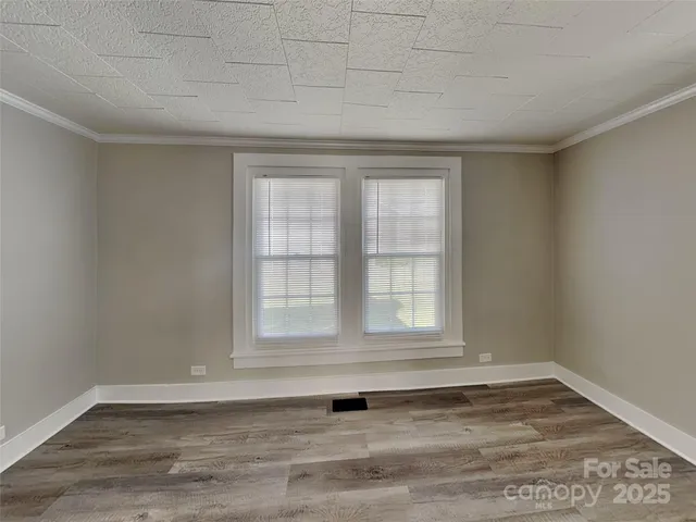 an empty room with wooden floor and window