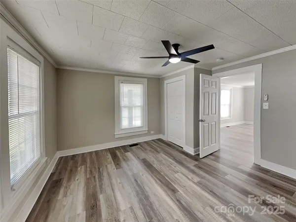 a view of empty room with wooden floor and fan