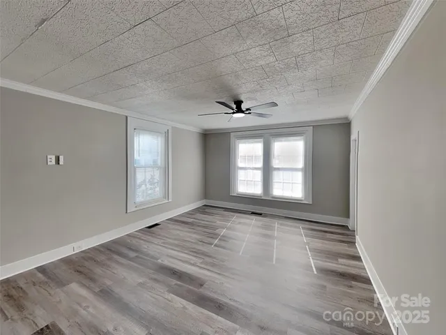 a view of an empty room with a window and wooden floor