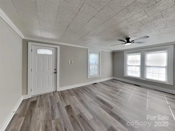 a view of an empty room and window and wooden floor