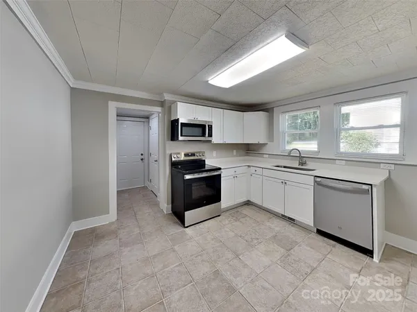 a large kitchen with white cabinets stainless steel appliances and window