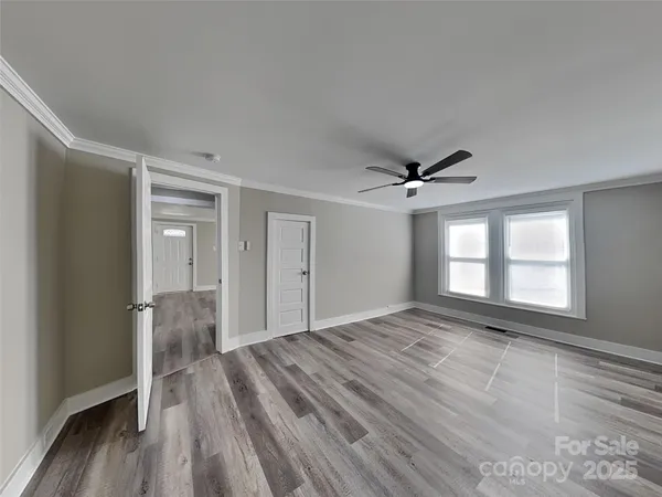 a view of empty room with wooden floor and fan