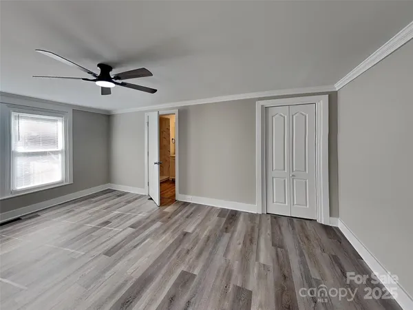 a view of empty room with wooden floor and fan