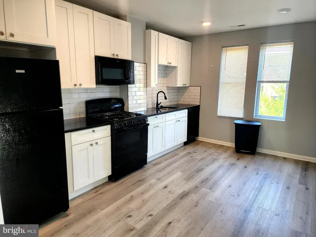 a kitchen with granite countertop a stove top oven a sink dishwasher and a refrigerator with wooden floor