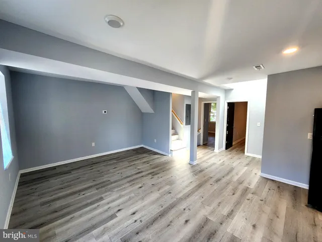 a view of an empty room with wooden floor and closet
