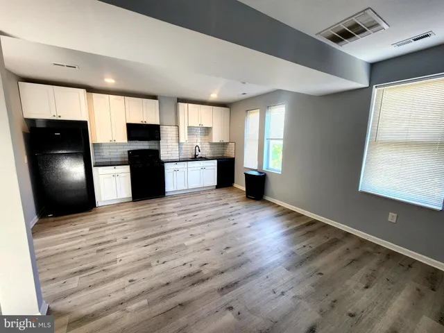 a kitchen with stainless steel appliances granite countertop a refrigerator a sink dishwasher a stove and a refrigerator with wooden floor