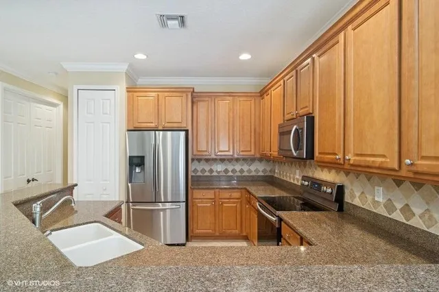a kitchen with stainless steel appliances granite countertop a refrigerator sink and stove