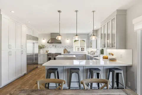 a dining hall with stainless steel appliances kitchen island granite countertop a dining table chairs and a white refrigerator