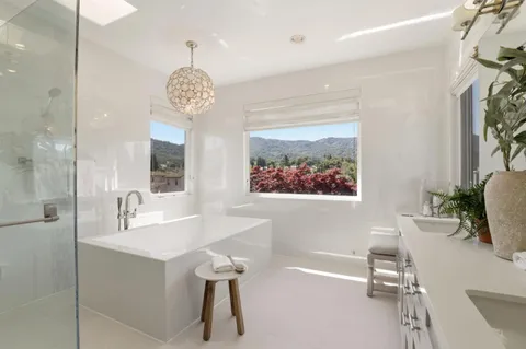 a bathroom with a tub sink shower and mirror