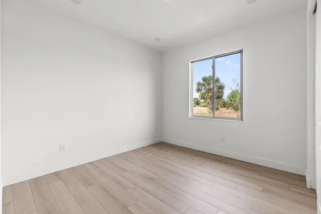 an empty room with wooden floor and window