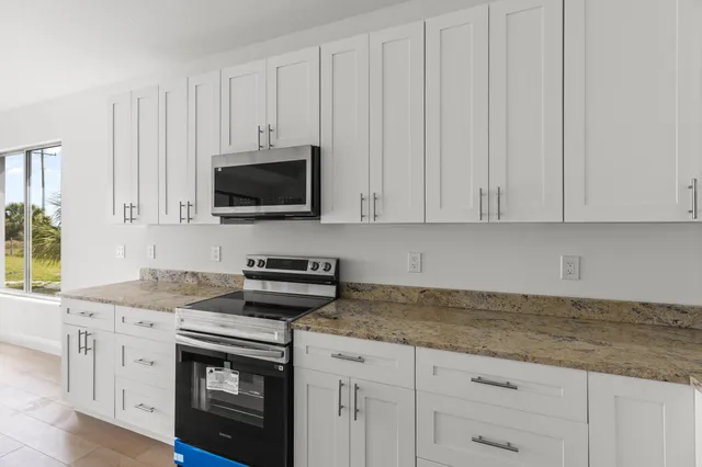 a kitchen with granite countertop white cabinets and a stove with wooden floor
