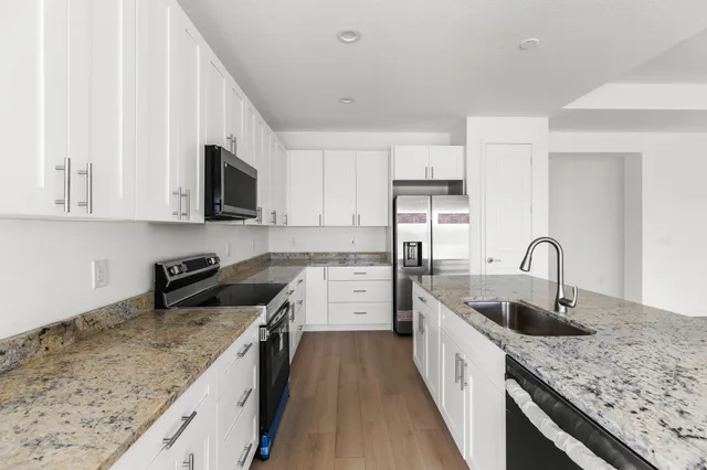 a kitchen with stainless steel appliances granite countertop a sink stove and refrigerator