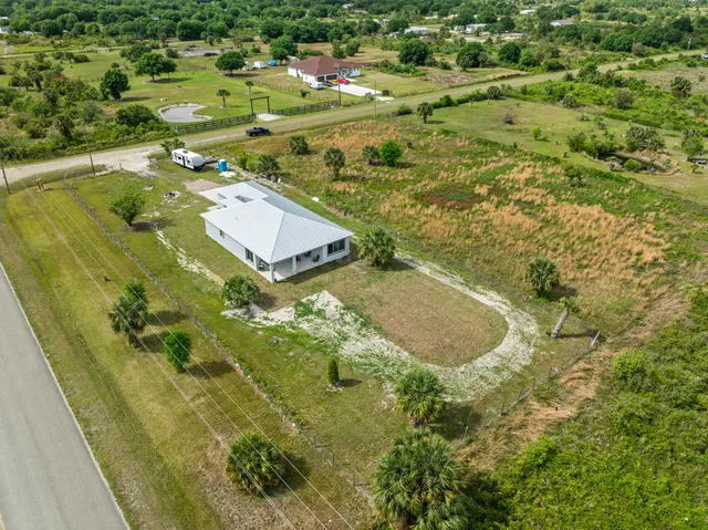 a aerial view of a residential houses with outdoor space and trees