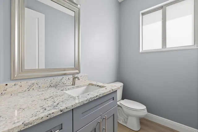 a bathroom with a granite countertop toilet sink and mirror