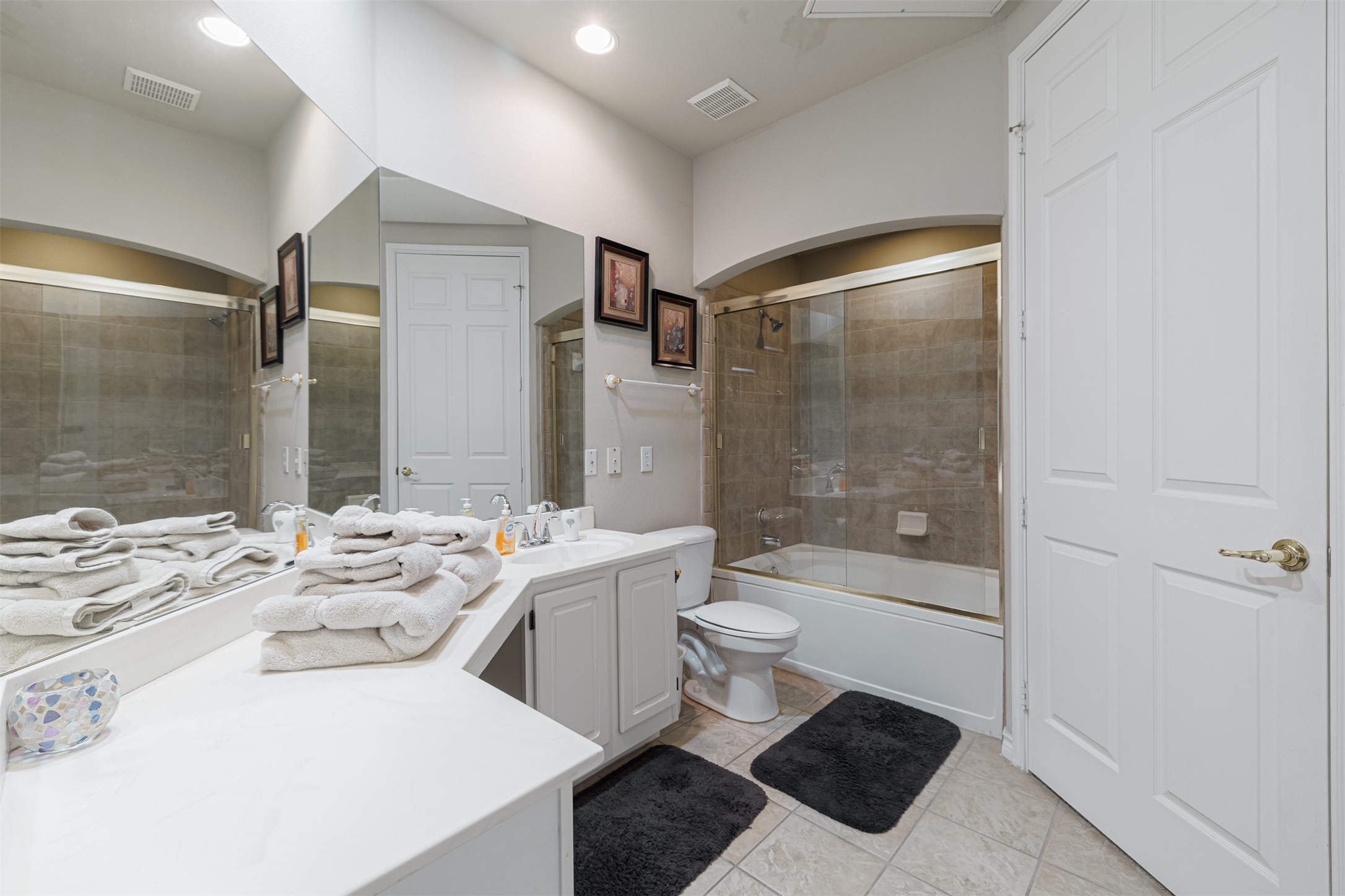 2400 McCue Road, Unit 248 Houston, TX 77056 - Photo 8 of 24 Spacious bathroom featuring a sleek vanity with ample counter space, a large mirror, and a glass-enclosed shower-tub combo, all accented by elegant tile flooring.