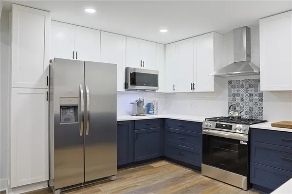 a kitchen with stainless steel appliances granite countertop a stove a refrigerator and a sink with wooden floor