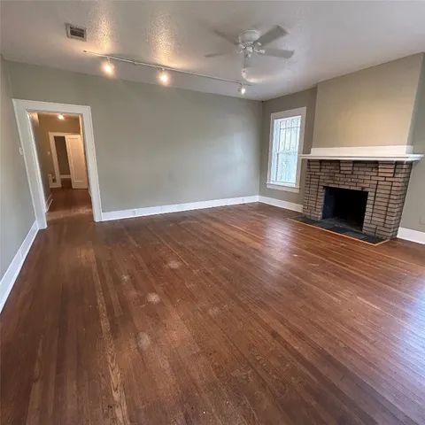 an empty room with wooden floor fireplace and windows