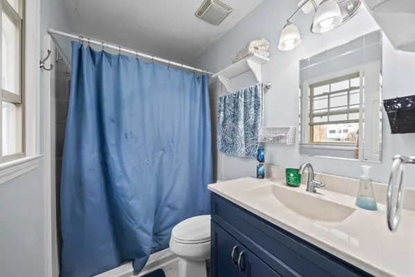a bathroom with a granite countertop sink toilet a mirror and a shower