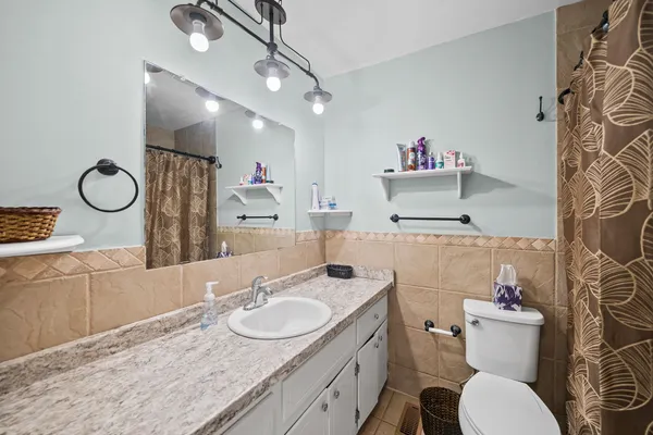 a bathroom with a granite countertop double vanity sink mirror and toilet