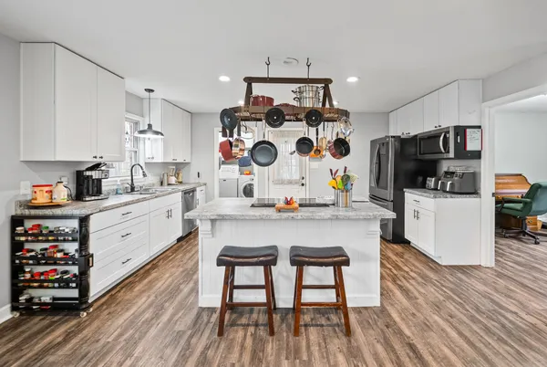 a large white kitchen with a large window a sink and stainless steel appliances