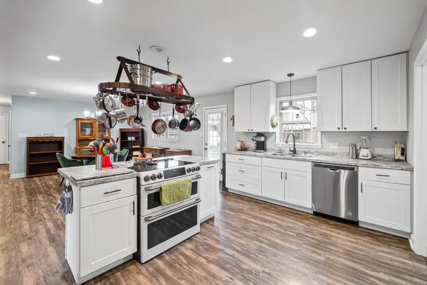 a kitchen that has a lot of white cabinets and wooden floor