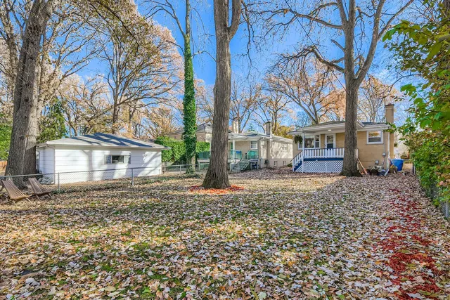 a view of a house with a yard covered with large trees