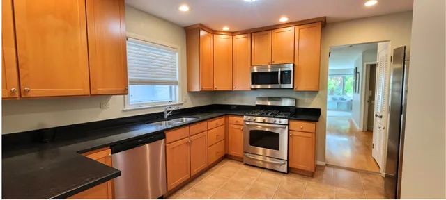 a kitchen with stainless steel appliances granite countertop a stove a sink and a microwave