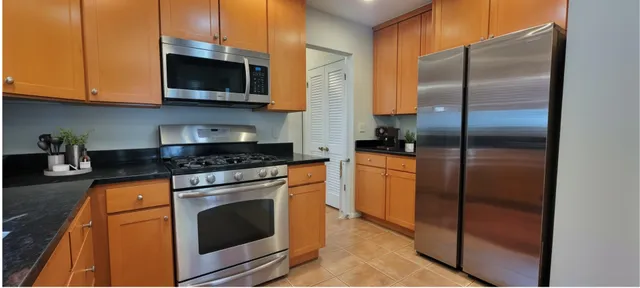 a kitchen with stainless steel appliances granite countertop a stove a refrigerator and a microwave