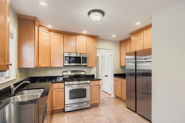 a kitchen with stainless steel appliances granite countertop a stove a refrigerator and a sink