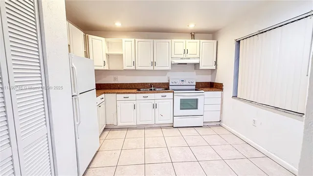 a kitchen with white cabinets and white appliances