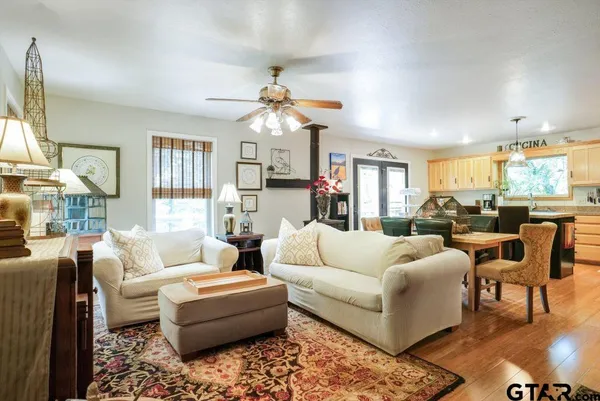 a living room with furniture a chandelier and a dining table with kitchen view