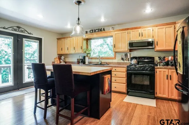 a kitchen with a stove a sink dishwasher a dining table and chairs with wooden floor