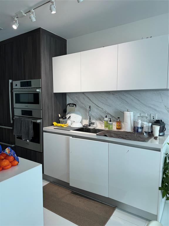 851 Northeast 1st Avenue, Unit 2606 Miami, FL 33132 - Photo 6 of 30 a kitchen with granite countertop a sink a stove and cabinets