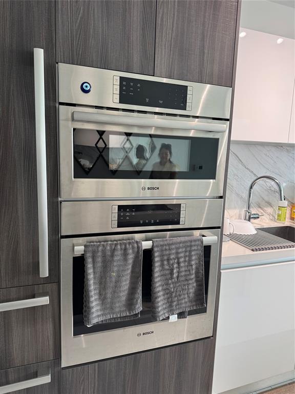 851 Northeast 1st Avenue, Unit 2606 Miami, FL 33132 - Photo 8 of 30 a stove top oven sitting inside of a kitchen with stainless steel appliances wooden cabinets
