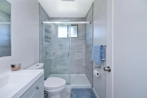 a bathroom with a granite countertop toilet a sink and shower