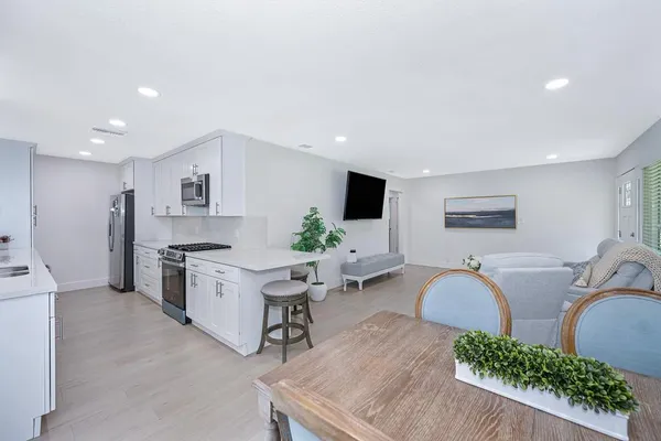 a living room with furniture kitchen view and a potted plant