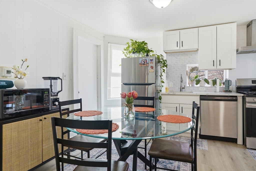 43 Wamesit Street Lowell, MA 01852 - Photo 15 of 34 a kitchen with stainless steel appliances a dining table chairs and a refrigerator