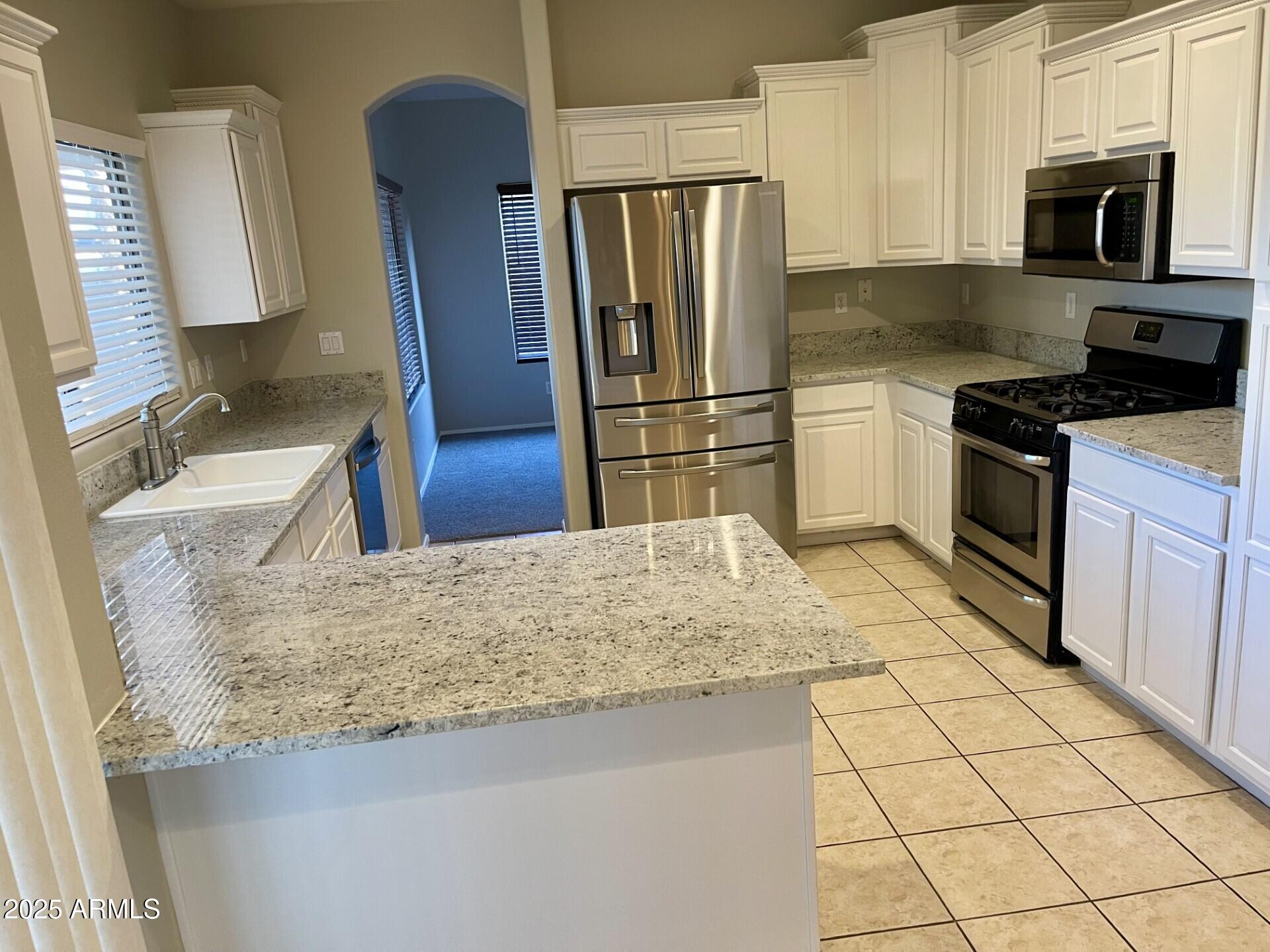 3613 North 127th Drive Avondale, AZ 85392 - Photo 3 of 12 a kitchen with stainless steel appliances granite countertop a sink stove and refrigerator
