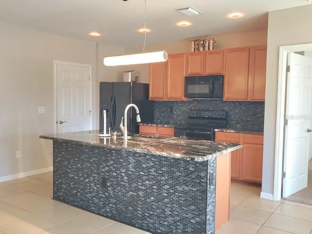 a kitchen with stainless steel appliances granite countertop a sink a stove and a refrigerator