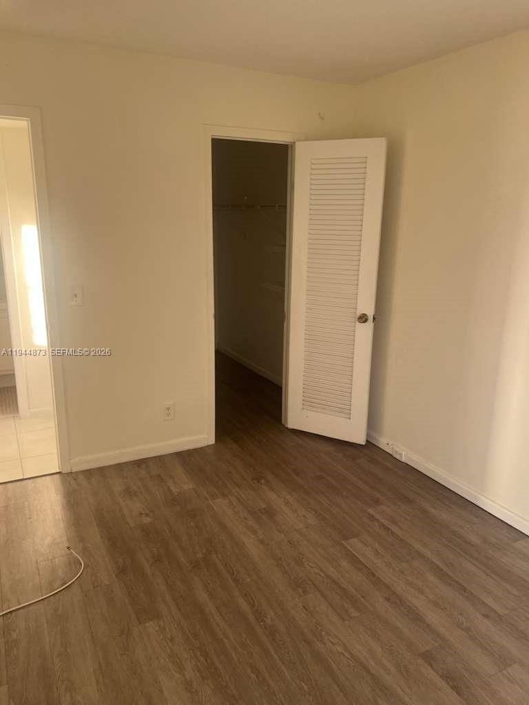 528 Mansfield M, Unit 528 Boca Raton, FL 33434 - Photo 12 of 14 a view of an empty room with wooden floor and a window
