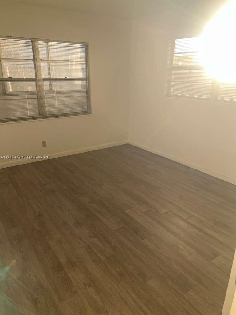 528 Mansfield M, Unit 528 Boca Raton, FL 33434 - Photo 9 of 14 an empty room with wooden floor and windows