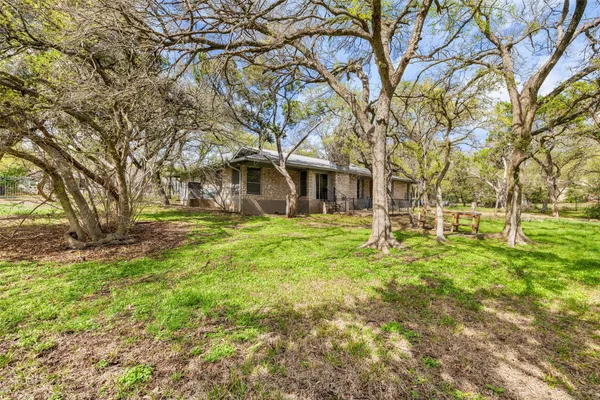 a yard with a tree in front of the house