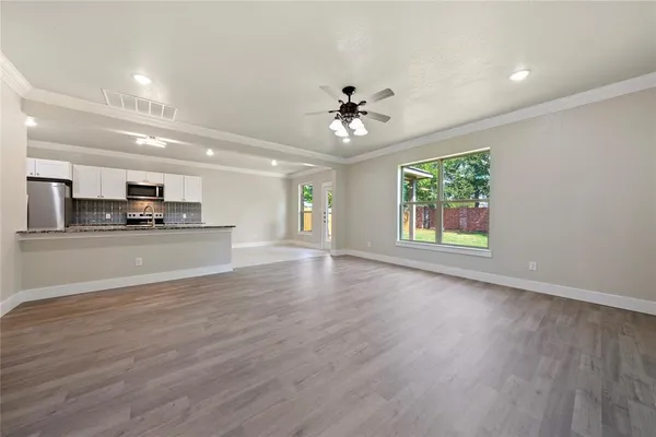 a view of an empty room with window and wooden floor