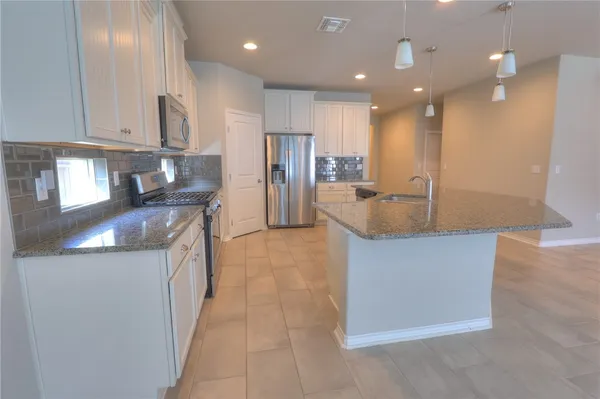 a kitchen with stainless steel appliances granite countertop a refrigerator a sink and a stove