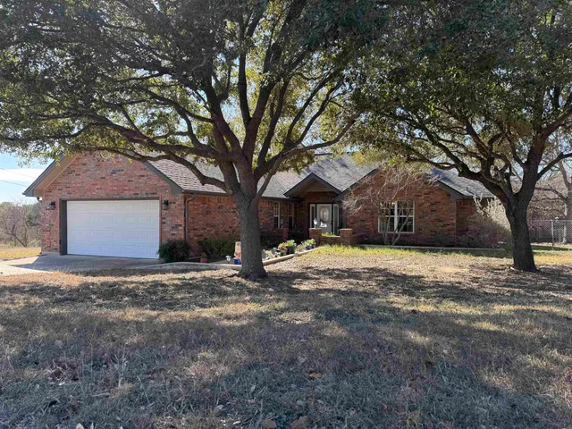 a view of a house with a yard and large tree