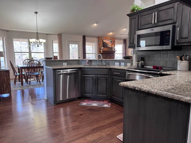 a kitchen with stainless steel appliances granite countertop wooden floors and granite counter tops